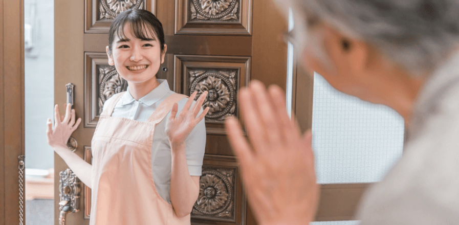 帰り際に玄関で、お客様に笑顔で手を振る女性スタッフの写真
